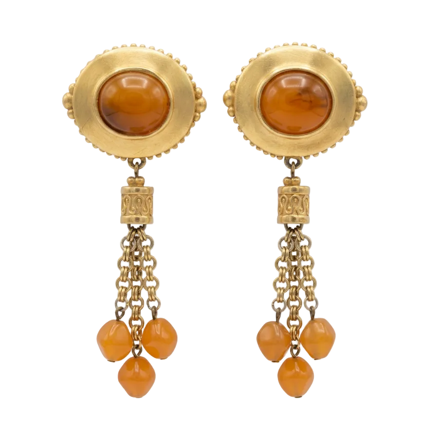 A pair of vintage gold-toned dangle earrings featuring oval amber cabochons in the center, connected by ornate links to three dangling amber beads, shown against a plain white background.