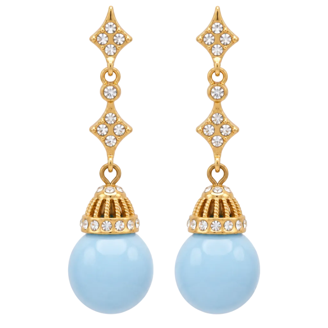 A pair of gold drop earrings featuring clear rhinestones in diamond-shaped and filigree details, with large light blue oval pearl-like drops at the bottom, shown on a plain white background.