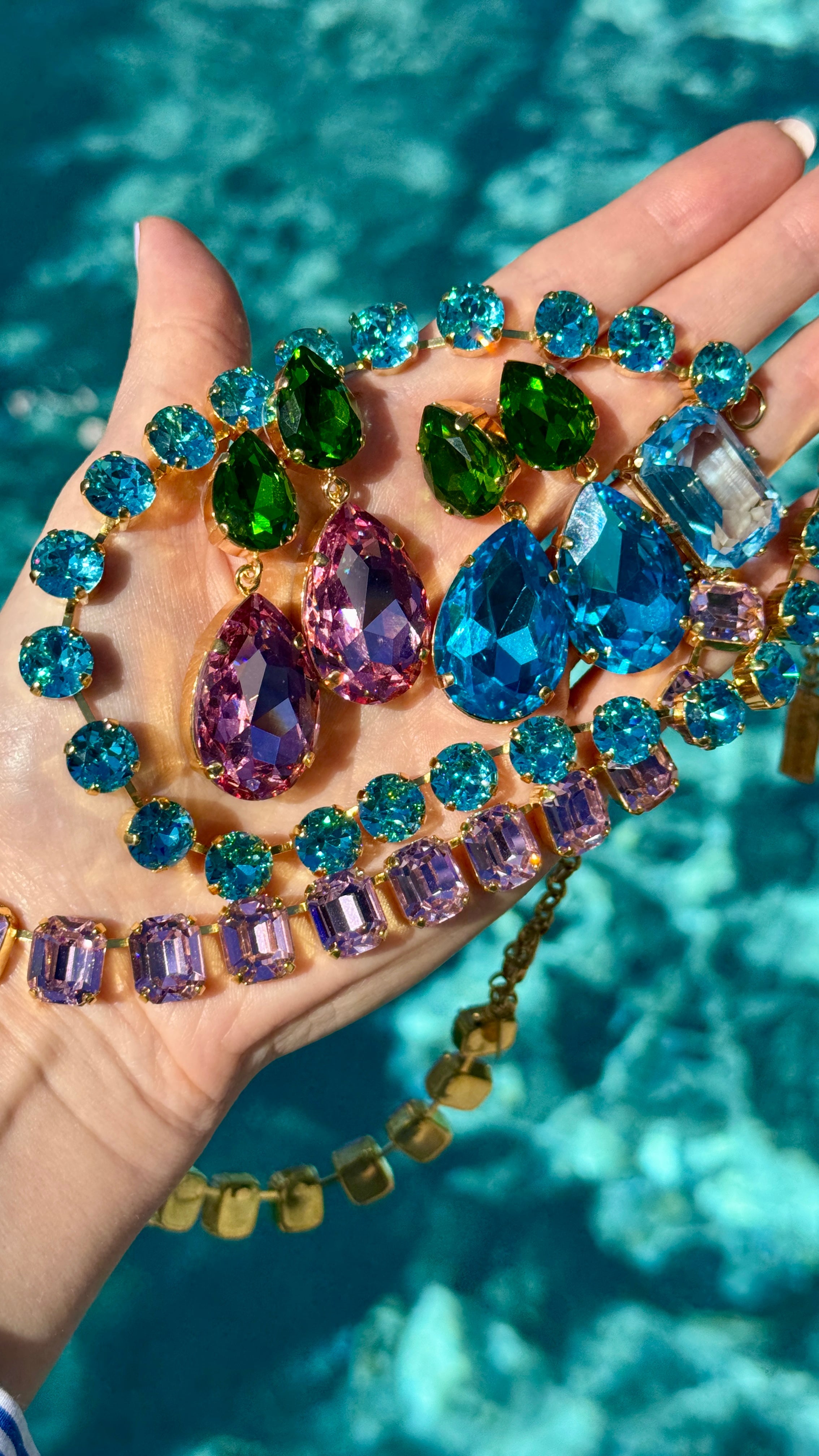 Hand holding colorful crystal necklaces