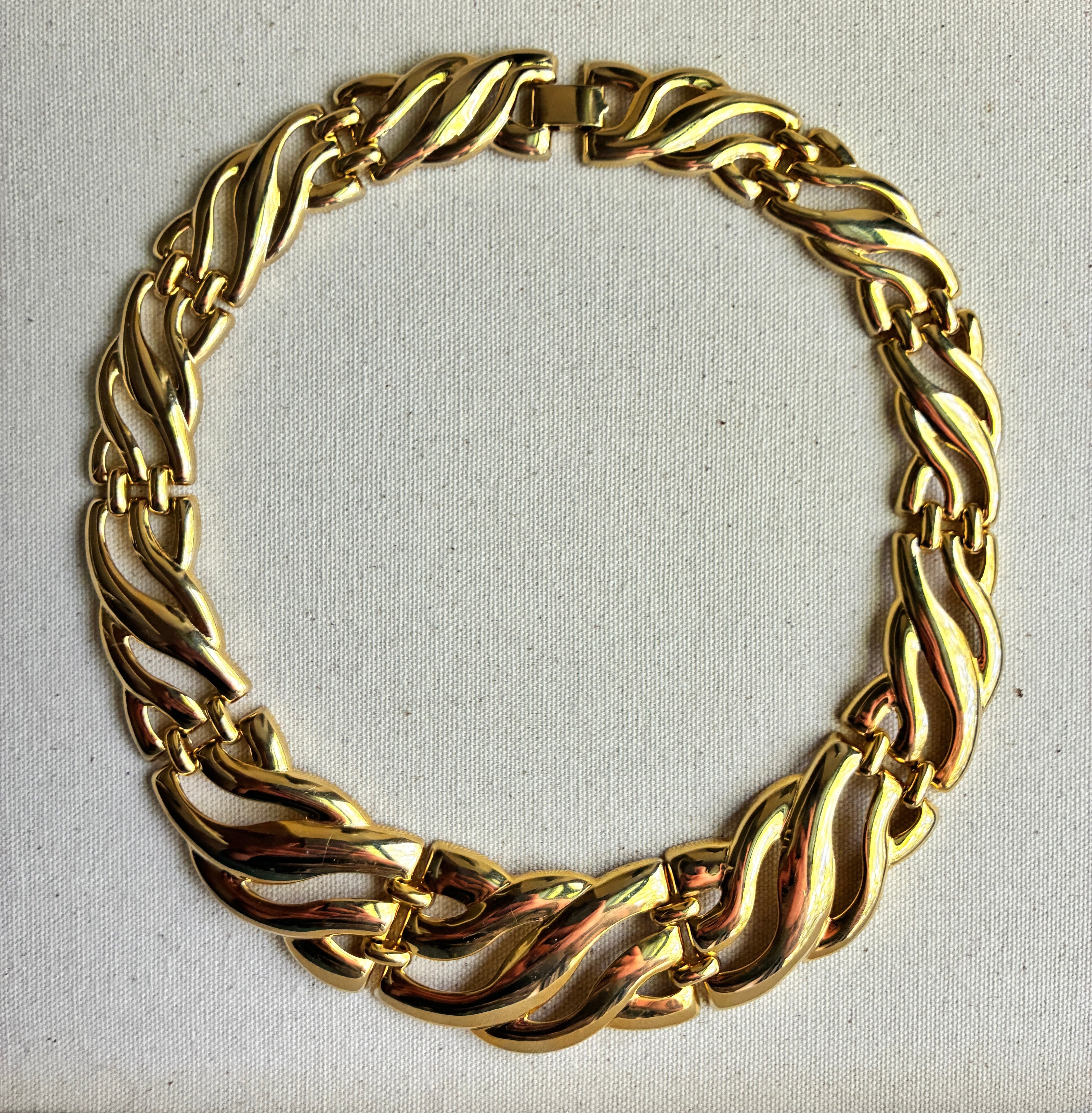 Gold chain collar necklace on a light gray background