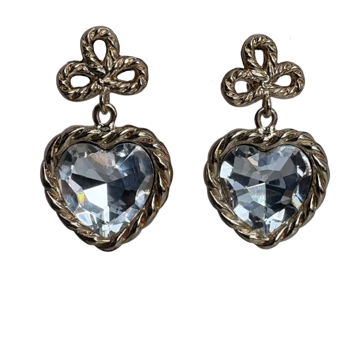 A pair of antique bronze heart-shaped drop earrings with faceted clear glass or crystal centers, set against a plain white background.