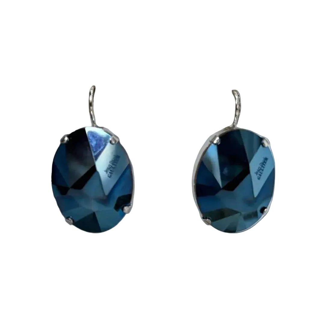 A pair of oval drop earrings featuring faceted dark blue glass stones in silver-toned prong settings with silver-tone hooks, shown on a plain white background.