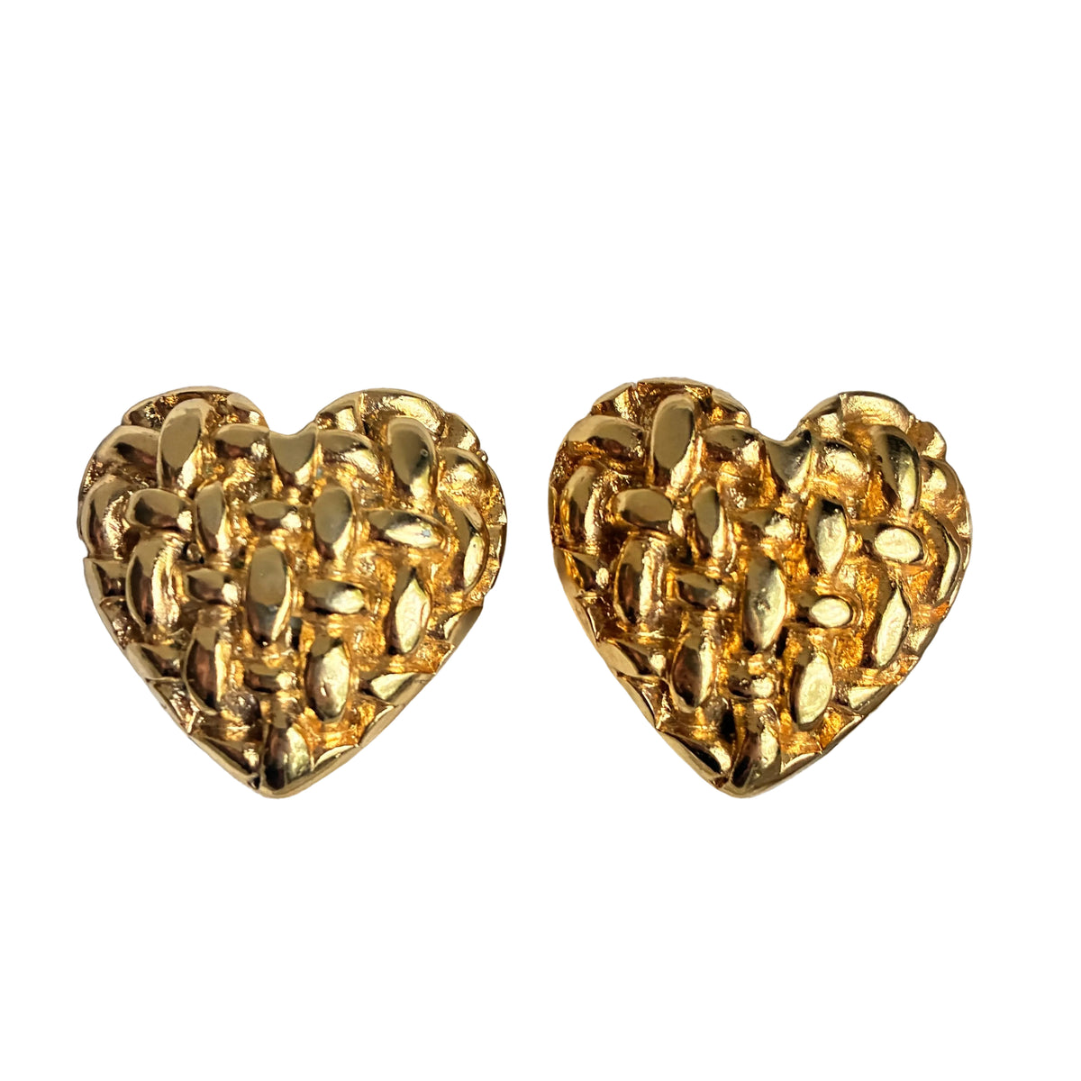 A pair of textured gold heart-shaped stud earrings displayed on a light gray jewelry box cushion.