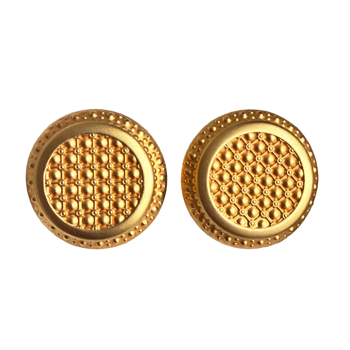 A pair of round gold-toned earrings with textured geometric patterns and beaded edges, displayed on a white fabric jewelry organizer.